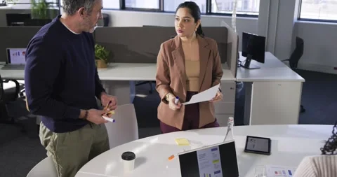 Diverse team demonstrating pie chart on tablet at office table writing notes Stock Footage 340881300