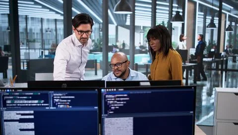 Diverse Team Of Developers Coding Software Projects On Desktop Computers In O Foto stock