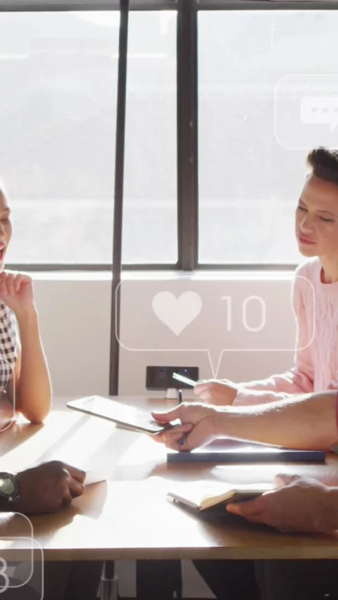 Diverse team discusses under floating social media icon, symbolizing tech Stock Footage 344783799