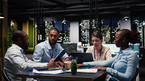 Diverse team of employees in office looking over paperwork documents Stock Footage 334041186