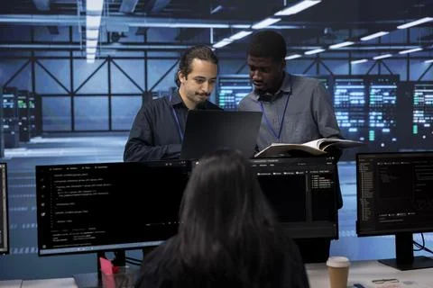 Diverse team of engineers in data center looking for firewall misconfigurations Stock Photos
