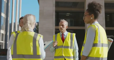Diverse team of engineers discussing project standing outdoors downtown Video stock 156449111