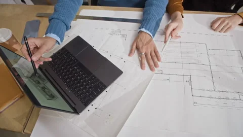 Diverse Team Members Working Together on Laptop and Floor Plan in Office Stock Footage 327851407
