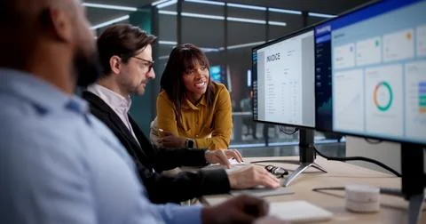 Diverse Team Of Office Workers Analyzing Billing Spreadsheets On Computers. S Foto stock