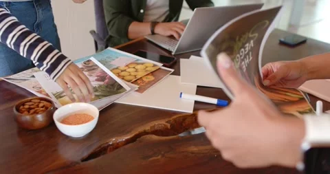 Diverse team reaching, passing, finalizing food layouts at live-edge table while Stock Footage 335895810