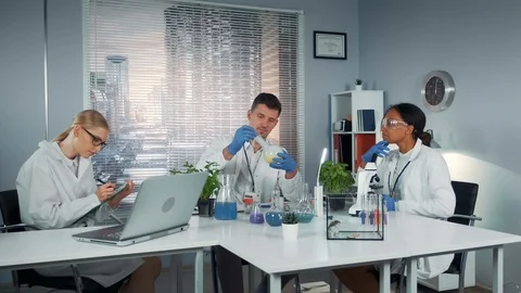 Diverse team of research scientists observing collegue's experiment with liquid Stock Footage 115253017