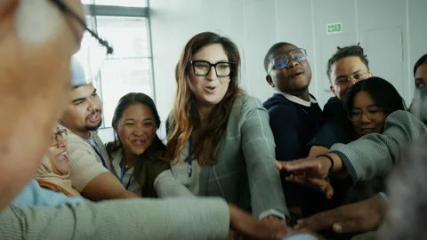 Diverse team shows unity and triumph by putting hands together in a huddle Stock Footage 336049072