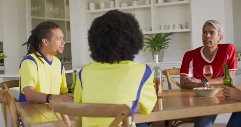 Diverse team sitting at kitchen table left man lowering bottle causing plain T Stock Footage 340613875