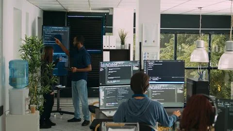 Diverse team of software engineers analyzing code on wall screen tv Stockfoto's