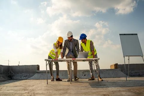Diverse team of specialists with computer on construction site. Building project Stock Photos