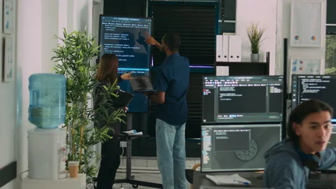 Diverse team of system developers analyzing code on big tv screen Video stock 221744180