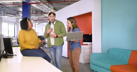 Diverse team tapping tablet while explaining concept and tilting laptop to Stock Footage 340968794
