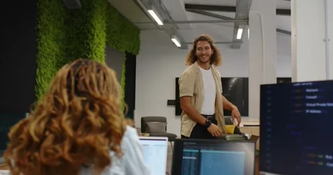 Diverse team typing on laptop at desk man checking smartphone walking over Видео 341027055