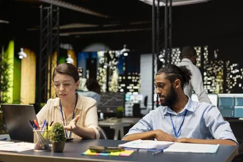 Diverse team using laptop at office desk, cooperating on computer tasks 库存照片