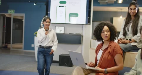 Diverse team watching speaker holding mic showing mockups at work as African Stock Footage 345750486