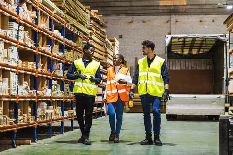 Diverse team of workers walking in lumberyard warehouse Fotos de archivo