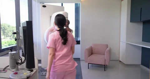 Diverse tech in pink scrubs and patient responding to monitor, tech guiding her Stock Footage 335683271