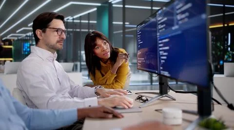 Diverse Tech Team Collaborates Closely Coding Software At Busy Office Desks.  库存照片
