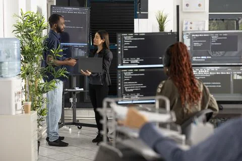Diverse Tech Team Discussing Software Code and Analytics In Open Workspace Stock-Fotos