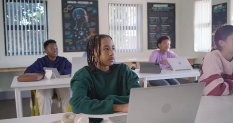 Diverse teens at laptops in classroom watching speaker reacting smiling at male Stockbeeldmateriaal 340811027