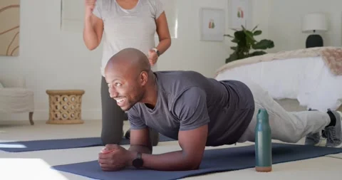 Diverse trainer kneeling behind man in bedroom fixing form, checking watch and Video stock 345037788