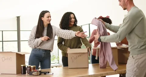 Diverse volunteers finding donation boxes and jars sorting items packing them Stock Footage 342595421