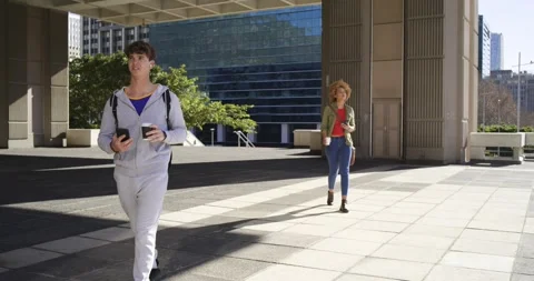 Diverse walkers exiting canopy walking plaza checking phones sipping coffee Stock Footage 341320053