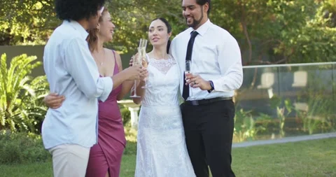 Diverse wedding group celebrating bride in lace gown raising champagne flutes Stock Footage 342596995