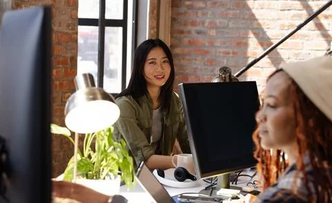 Diverse women collaborating on coding project at modern office, smiling and f Foto stock