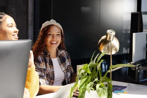 Diverse women collaborating on coding project at modern office, smiling and e Stock Photos