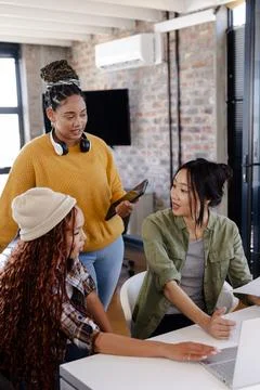 Diverse women collaborating on coding project in modern office, using laptop  Foto stock
