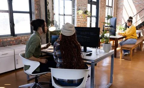 Diverse women collaborating on coding project in modern office, focused and 写真素材
