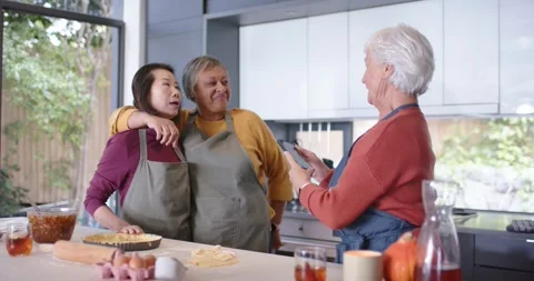 Diverse women posing in aprons at kitchen island right woman holding phone Stock Footage 339251570