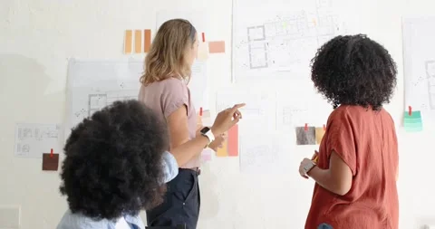 Diverse women team checking plans swatches pinned at studio after seated woman Stock Footage 341394269
