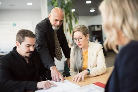 Diverse work team in office looking files at table Stock Photos