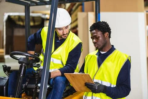 Diverse workers collaborating on forklift operations in warehouse Foto stock