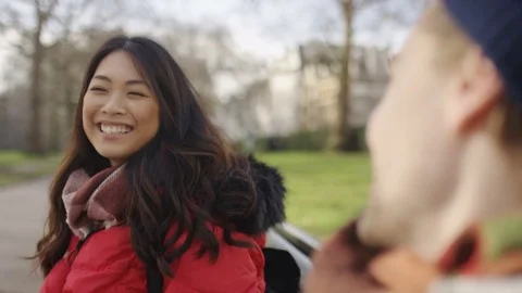 Diverse young couple talking on a park bench 84667781