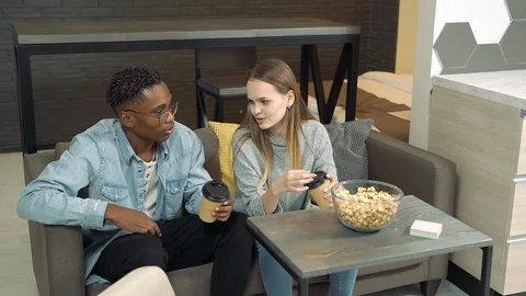 Diverse young couple talking while sitting on a sofa in a living room. Stock Footage 126238667