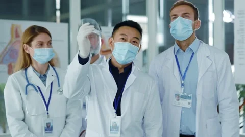 Diverse young doctors team communicating in medical office wearing masks agree Stock Footage 142846078