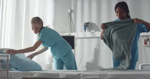 Diverse young nurses making bed and cleaning in hospital ward Stock Footage 149301554