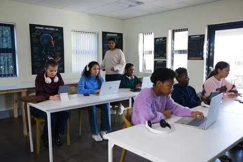 Diverse youth working on laptops and tablet in classroom with headphones, Stock-Fotos