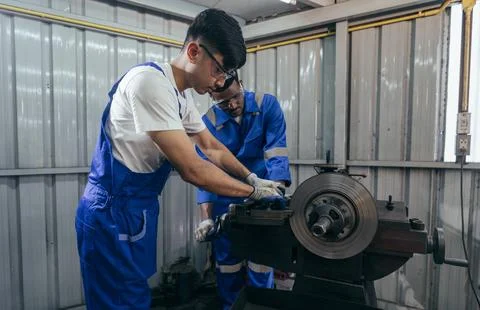 Diversity mechanic worker using metal lathe machine at the factory Stock Photos