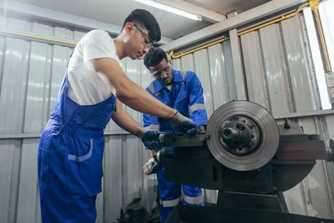 Diversity mechanic worker using metal lathe machine at the factory Stock Photos