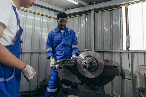 Diversity mechanic worker using metal lathe machine at the factory Stock Photos