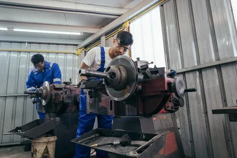 Diversity mechanic worker using metal lathe machine repairing at auto repai.. Stock Photos