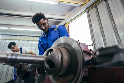 Diversity mechanic worker using metal lathe machine repairing at auto repai.. Stock Photos