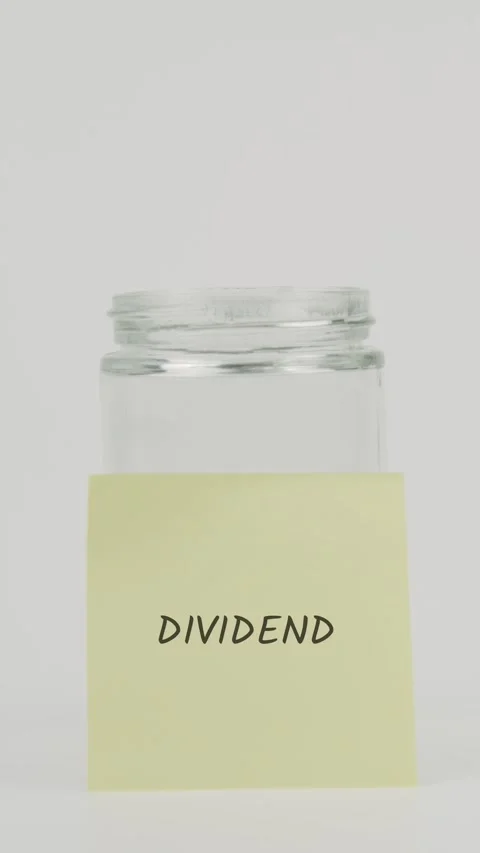 Dividend text or word on yellow sticky note attached to glass jar with hand Stock Footage 311720153