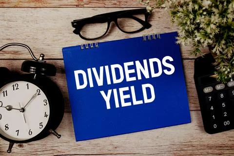 Dividends Yield text with alarm clock and calculator on wooden background Stock Photos
