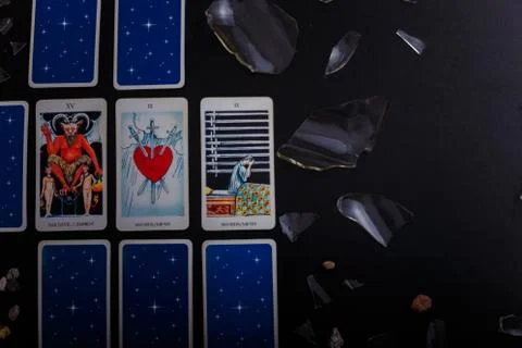 Divination cards alignment. Devil and swords. Black background, broken glass Stock Photos