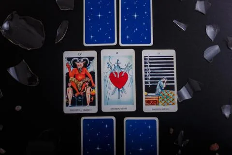 Divination cards alignment. Devil and swords. Black background, broken glass Stock Photos